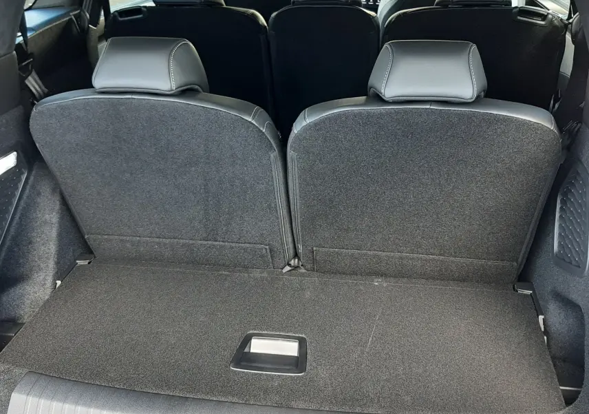 Vue arrière intérieure du Peugeot 5008 bleu Ingaro 2025, montrant la troisième rangée de sièges et le coffre spacieux.