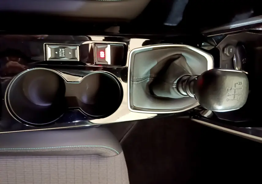 Vue rapprochée de la console centrale noire du Peugeot 2008 2021, avec levier de vitesses manuel et porte-gobelets.