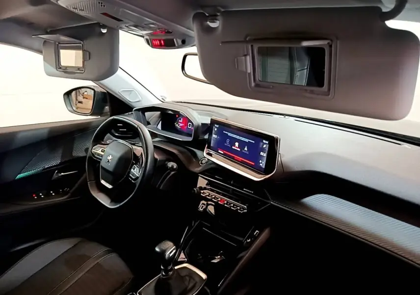 Vue intérieure côté conducteur du Peugeot 2008 noir 2021, tableau de bord avec écran tactile et volant multifonctions cuir.