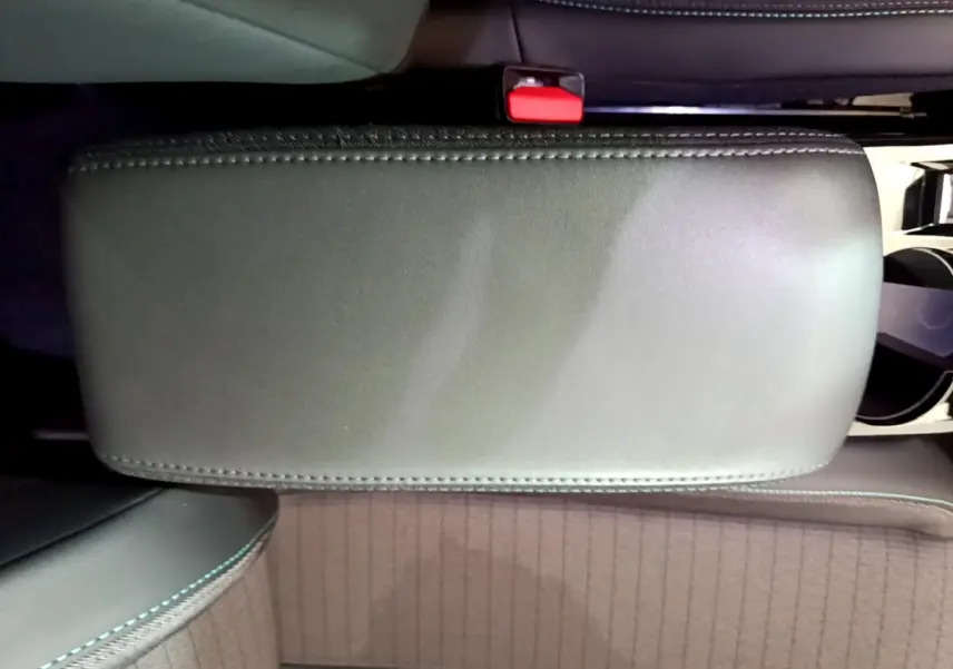 Vue plongeante sur l'accoudoir central noir et les sièges avant en tissu gris du Peugeot 2008 PureTech 130 S&S Allure Business.