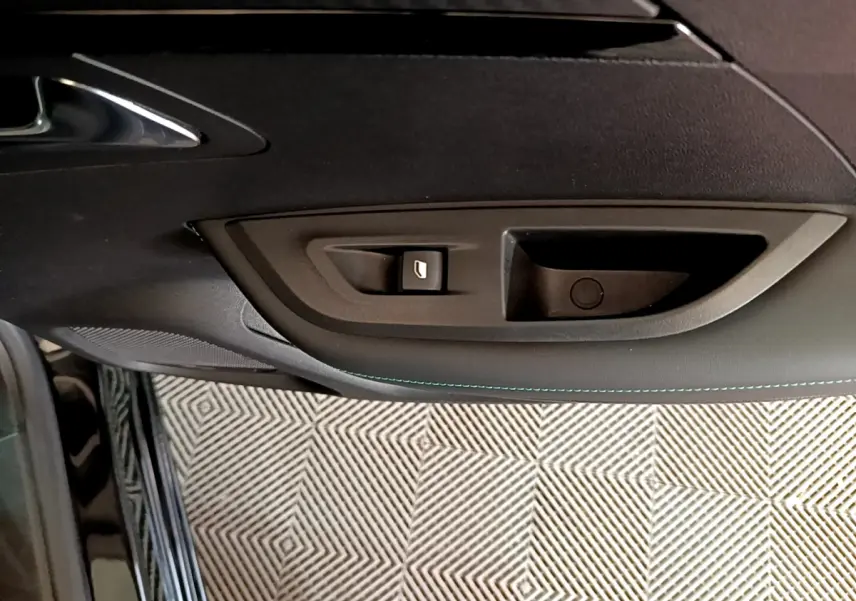 Poignée intérieure et commande de vitre côté gauche de la porte d'une Peugeot 2008 noire, finition Allure Business.