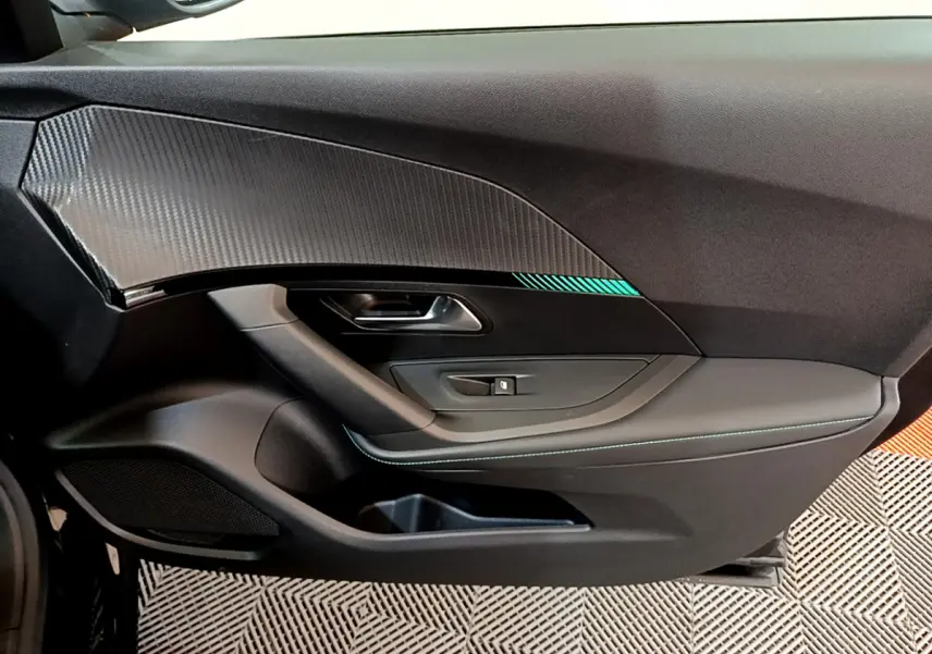 Vue côté gauche de la porte intérieure noire du Peugeot 2008 avec insert carbone et surpiqûres bleues.
