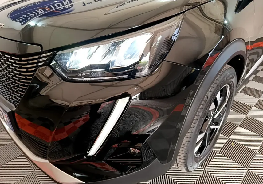 Gros plan sur l'avant droit noir brillant du Peugeot 2008 avec phares LED et jante alliage visible.