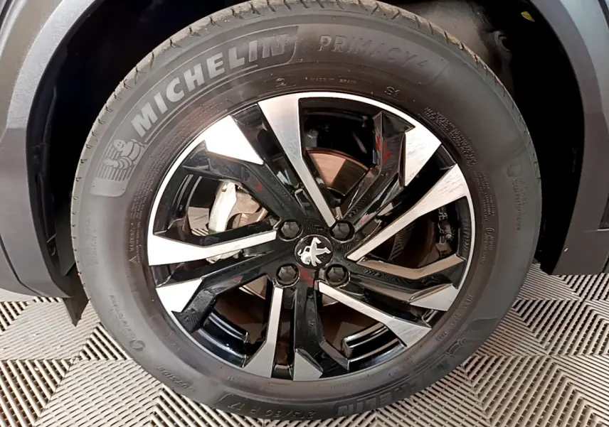 Gros plan sur la jante alliage bicolore noire et argent avec logo Peugeot, montée sur pneu Michelin Primacy 4.