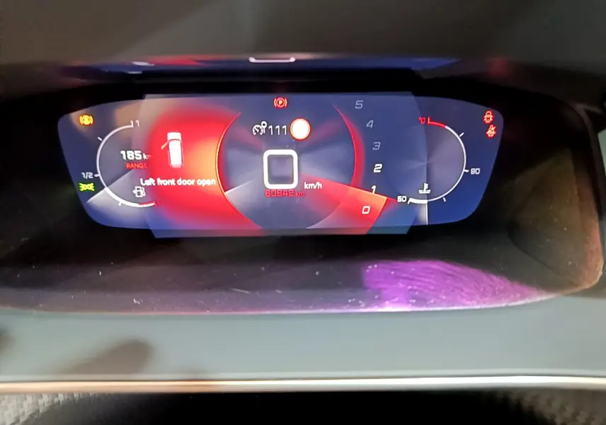 Gros plan sur le tableau de bord numérique du Peugeot 2008 2021, affichant vitesse, jauge et alertes en rouge et blanc.