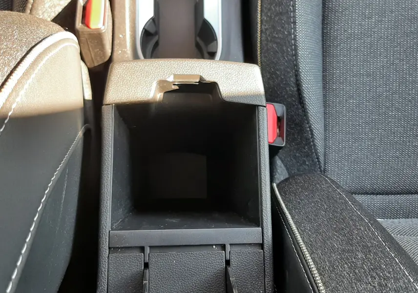 Vue plongeante sur le rangement central ouvert entre les sièges avant en tissu gris du Renault Captur II 2025.