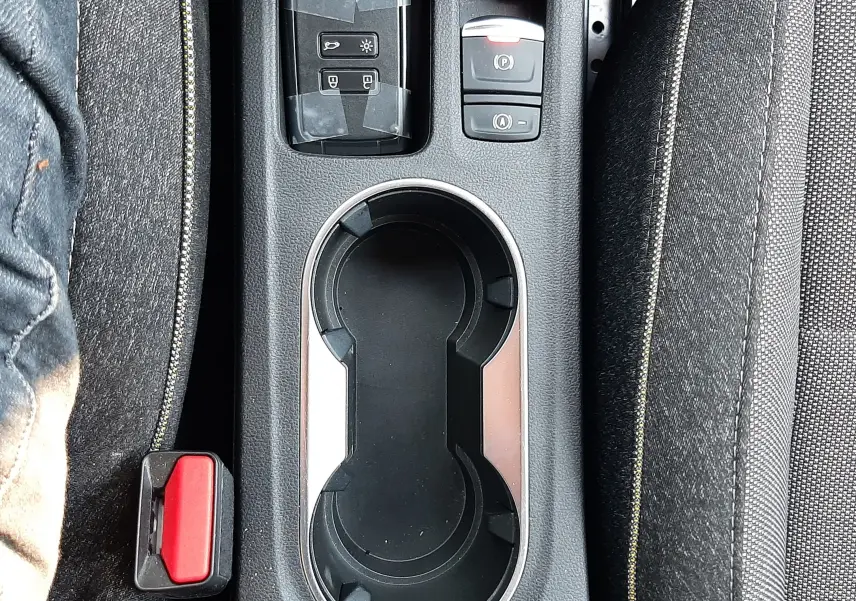 Vue plongeante sur la console centrale du Renault Captur gris Cassiopée, avec porte-gobelets et boutons de frein à main électronique.
