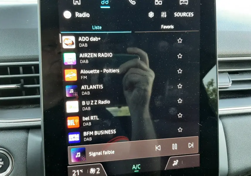 Écran tactile central du Renault Captur 2025 affichant la liste des radios, avec tableau de bord gris visible en arrière-plan.