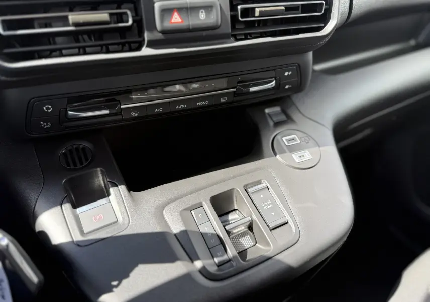 Vue rapprochée de la console centrale du Citroën Berlingo gris, montrant la commande de boîte automatique et les réglages climatiques.