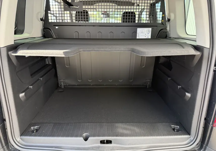 Coffre ouvert vu de l'arrière du Citroën Berlingo gris Artense, avec séparation grillagée et tablette de rangement.