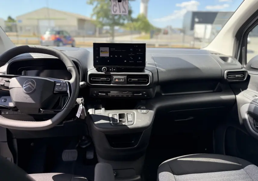 Vue intérieure avant du Citroën Berlingo gris Artense, tableau de bord moderne avec écran tactile central et volant multifonction.