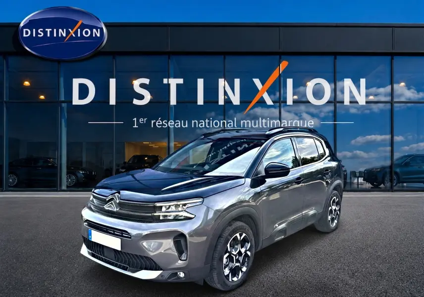 Citroën C5 Aircross gris en 3/4 avant droit, avec jantes alu et toit noir brillant devant showroom Distinxion.