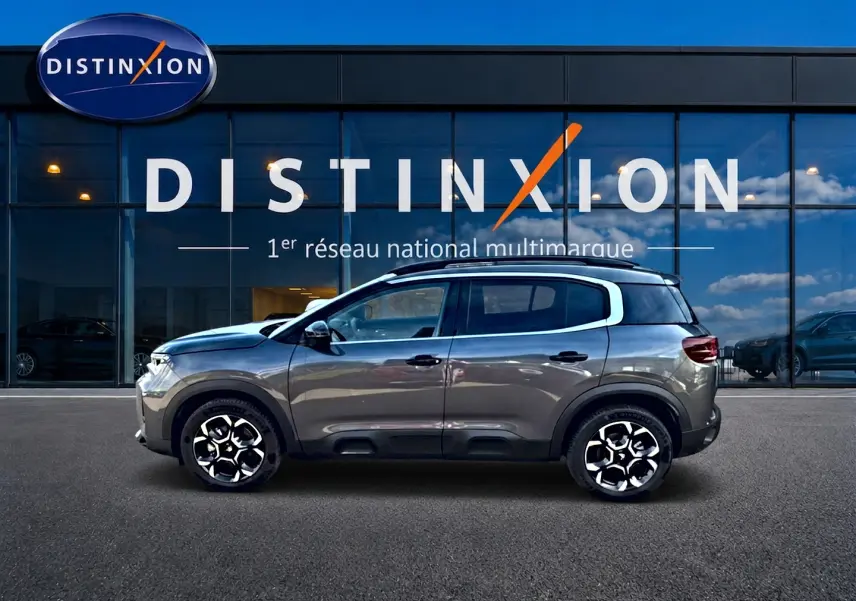 Profil côté gauche d'un Citroën C5 Aircross gris 2025 avec jantes alu et barres de toit visibles.