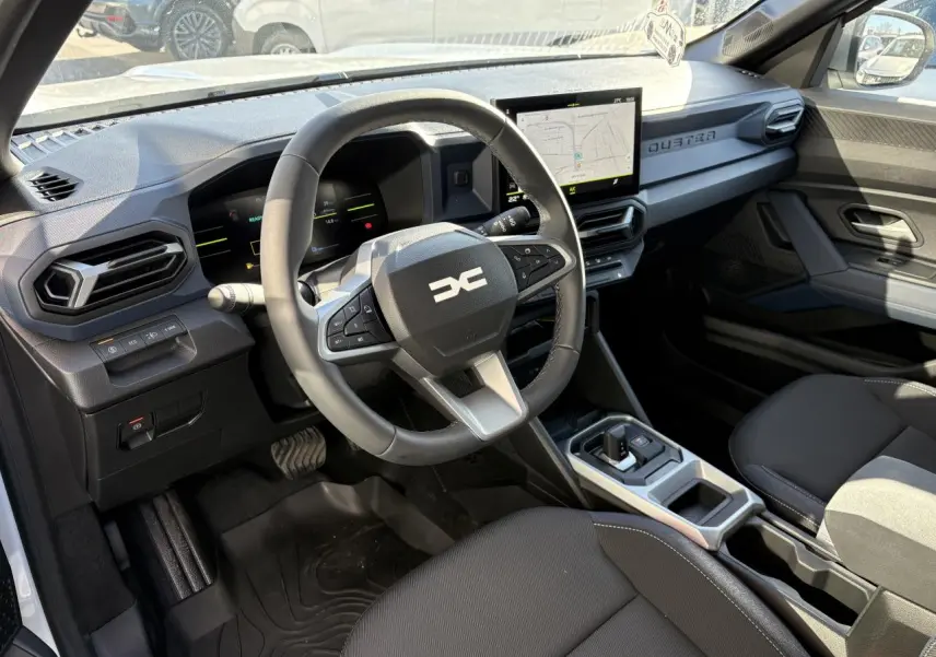 Vue intérieure côté conducteur du Dacia Duster 2024, avec tableau de bord digital et écran tactile central.