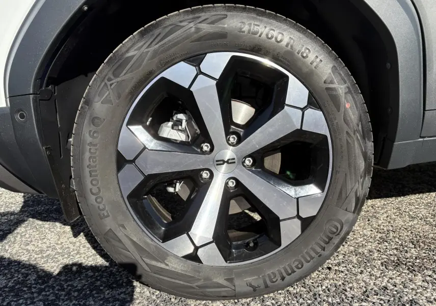 Gros plan sur la jante alliage 18 pouces noire et argent du Dacia Duster 1.6 Hybrid blanc métallisé, côté droit.