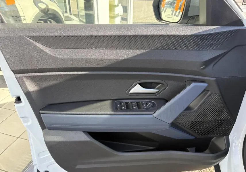 Vue côté gauche de la porte avant blanche du Dacia Duster 2024 avec commandes de vitres et poignée grise.