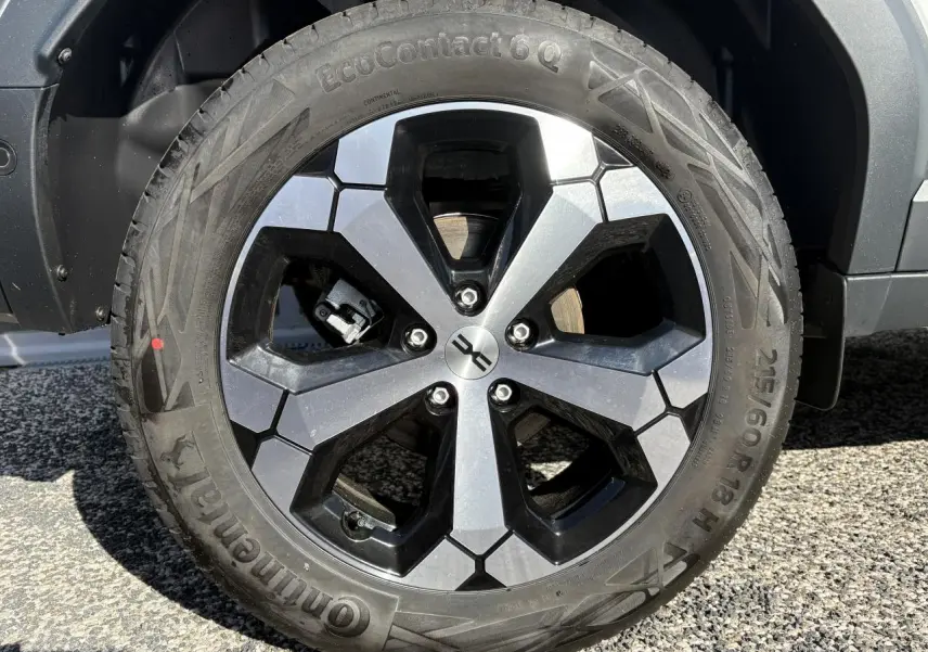 Gros plan sur la jante alliage 18 pouces noire et argent du Dacia Duster blanc métallisé 2024.