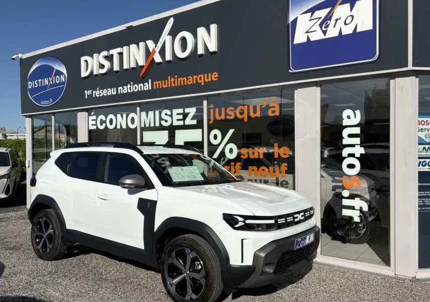 Dacia Duster blanc métallisé en 3/4 avant droit, avec barres de toit noires et jantes alliage 18 pouces.