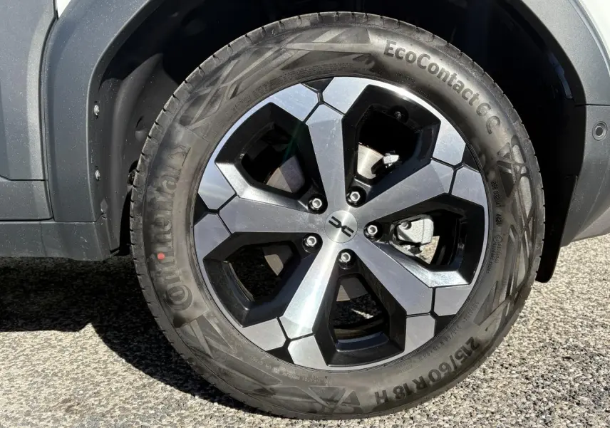 Gros plan sur la jante alliage 18 pouces noire et argent du Dacia Duster blanc métallisé, côté droit arrière.