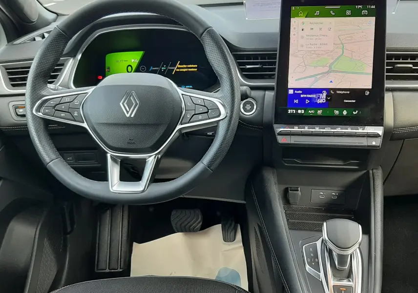 Vue intérieure centrée sur le volant et la console centrale avec écran tactile du Renault Symbioz blanc nacré 2025.