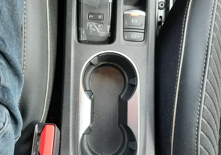 Vue plongeante sur la console centrale noire du Renault Symbioz blanc nacré, avec porte-gobelets et commandes électroniques.