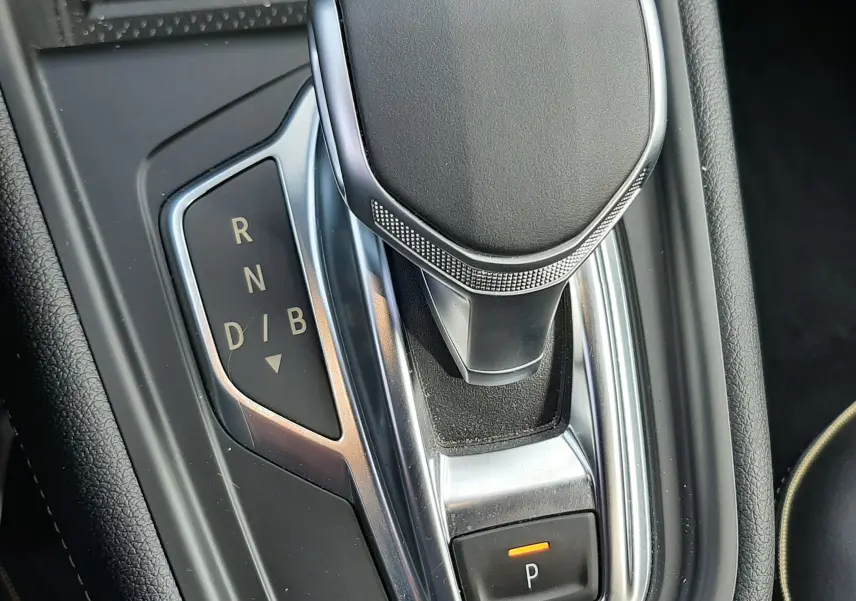Le levier de vitesses automatique noir et chrome vu de dessus dans l'habitacle du Renault Symbioz blanc nacré.