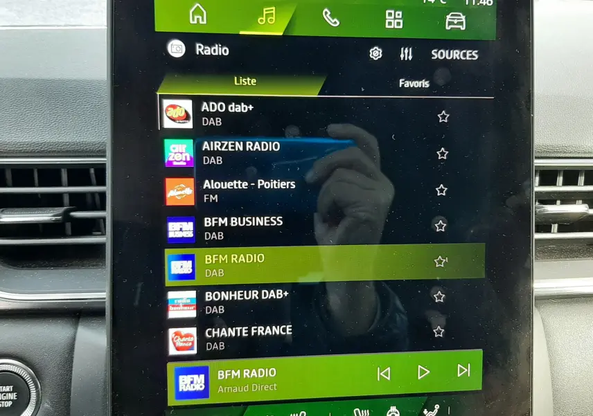 Écran tactile central du tableau de bord Renault Symbioz blanc nacré 2025, affichant la liste des radios DAB avec commandes climatisation en dessous.