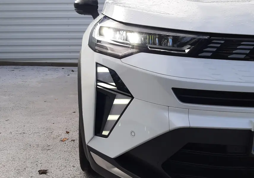 Vue avant gauche rapprochée du Renault SYMBIOZ blanc nacré, mettant en valeur ses phares LED et sa calandre moderne.