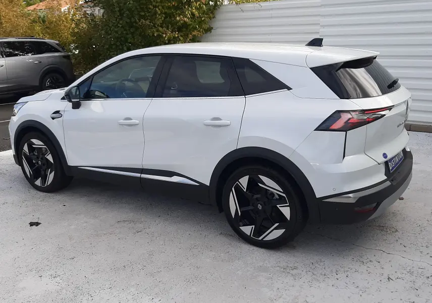 Vue 3/4 arrière droite du Renault Symbioz blanc nacré, soulignant ses jantes noires et design moderne.