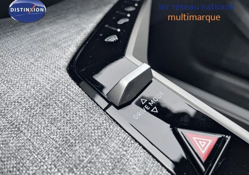 Gros plan sur la molette Drive Mode et le bouton de warning sur la console centrale tissu gris du Peugeot 5008 hybride 2025.