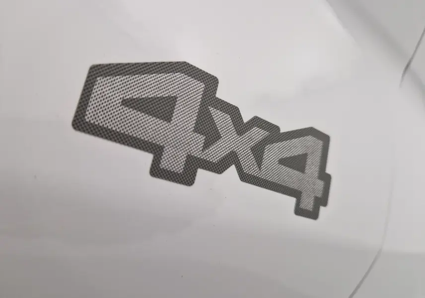 Gros plan sur l'autocollant 4x4 gris sur la carrosserie blanche du Dacia Duster 2024 version Extreme.