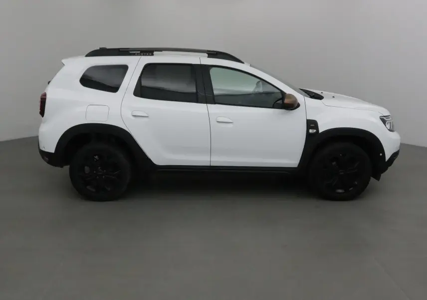 Profil côté gauche d'un Dacia Duster blanc 2024 avec jantes noires et coques de rétroviseurs marron.