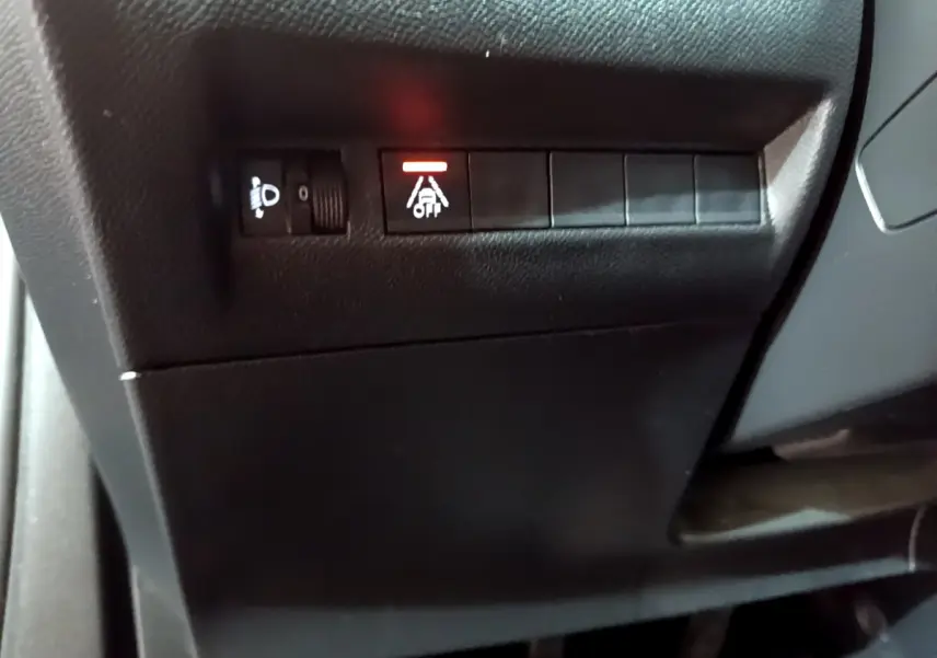 Gros plan sur les commandes de réglage des phares et d'alerte de franchissement de ligne dans le tableau de bord d'une Peugeot 2008.