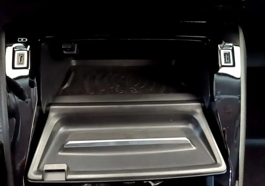 Vue rapprochée de la zone de recharge par induction et ports USB avant sur la console centrale noire du Peugeot 2008 gris clair.