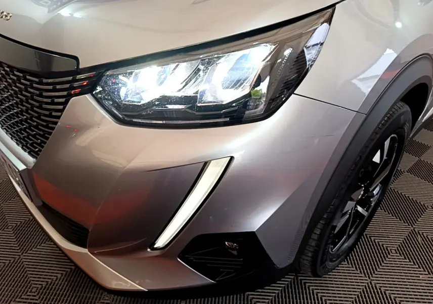 Gros plan sur l'avant droit gris clair du Peugeot 2008 2021, mettant en valeur le phare LED et la calandre noire.