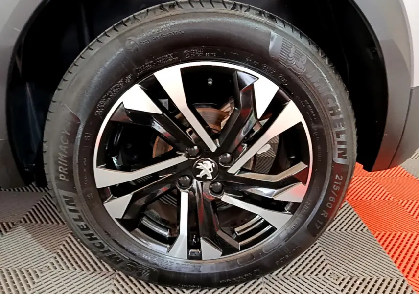 Gros plan sur la jante noire et argentée du côté droit du Peugeot 2008 gris clair, avec pneu Michelin visible.