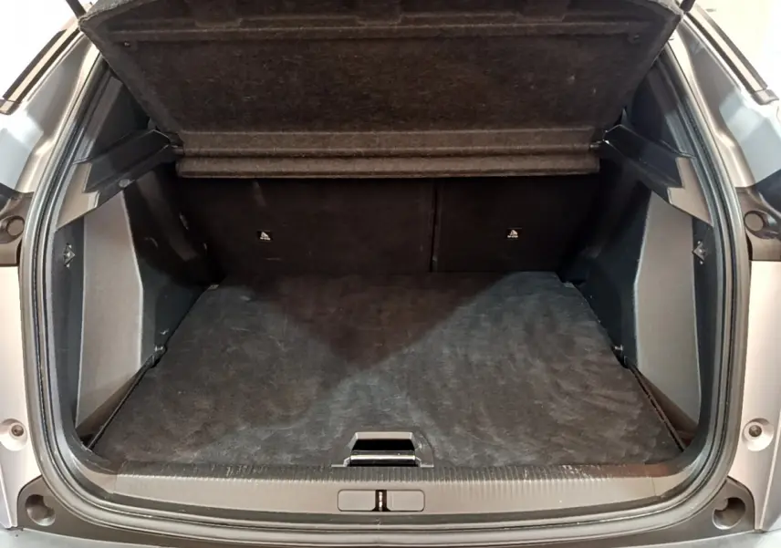Coffre ouvert vu de l'arrière d'un Peugeot 2008 gris clair, montrant un espace de chargement propre et spacieux.