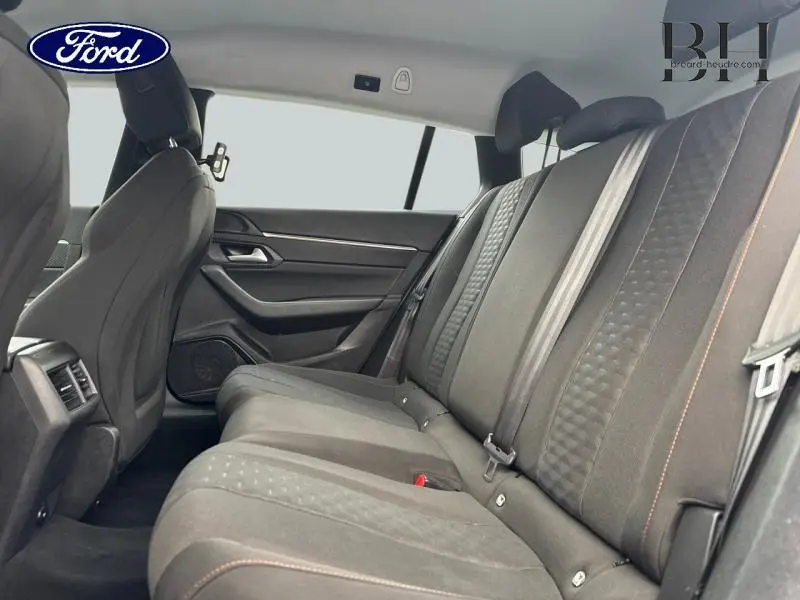 Vue latérale intérieure du côté droit montrant la banquette arrière tissu noir avec surpiqûres orange du Peugeot 508 SW gris Platinium.