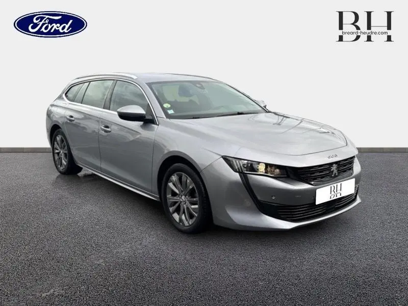Peugeot 508 SW gris Platinium vue 3/4 avant droit, avec calandre noire et jantes alliage visibles.
