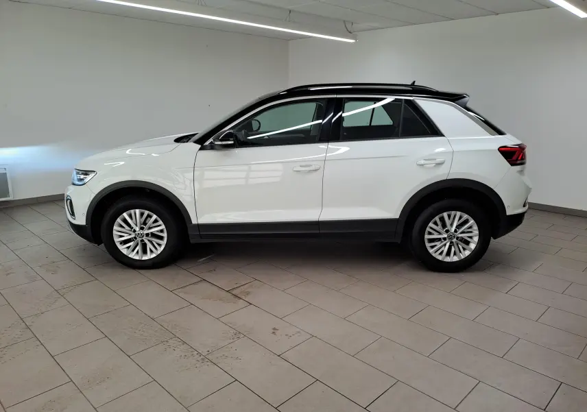 Vue de profil côté gauche d'un Volkswagen T-Roc 2022 blanc pur avec toit noir et jantes alliage en intérieur.