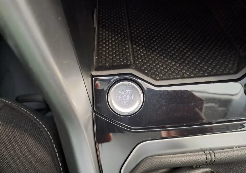 Bouton start/stop moteur en gros plan sur la console centrale noire du Volkswagen T-Roc blanc toit noir, vue intérieure rapprochée.