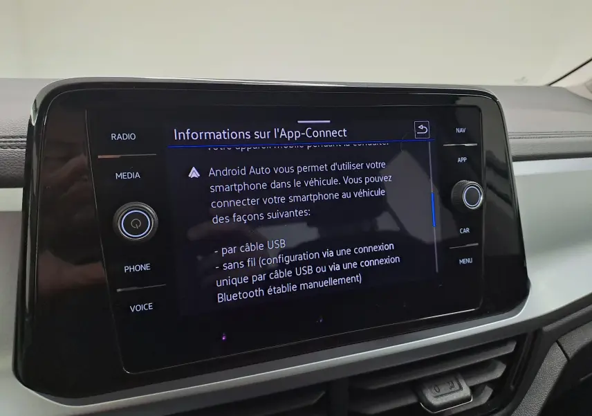 Vue intérieure centrée sur l'écran tactile du tableau de bord du Volkswagen T-Roc 2022 blanc toit noir, affichant les options App-Connect.