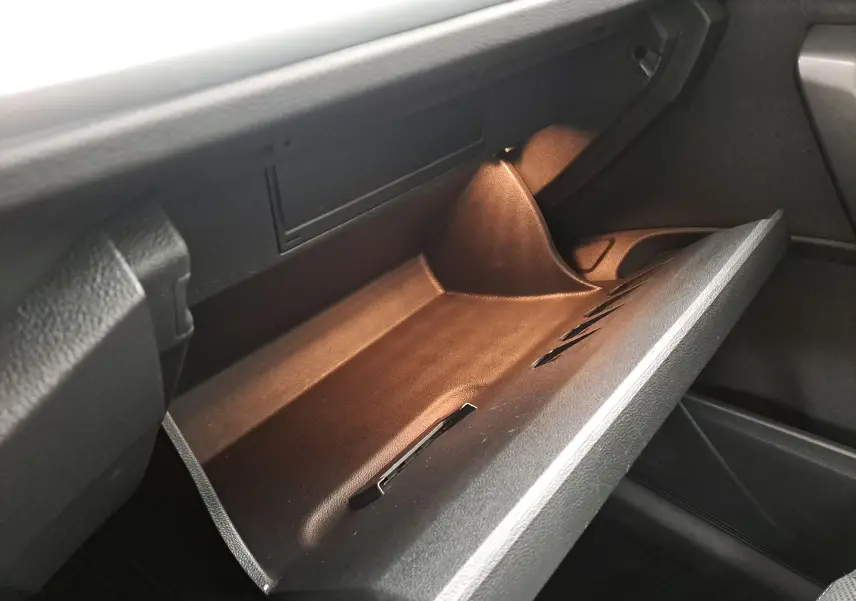 Gant de rangement ouvert côté passager du Volkswagen T-Roc 2022, intérieur noir avec éclairage intérieur doux.