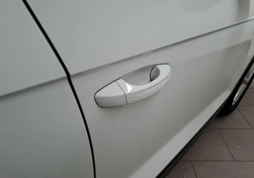 Gros plan sur la poignée de porte côté gauche du Volkswagen T-Roc blanc pur 2022 avec toit noir.