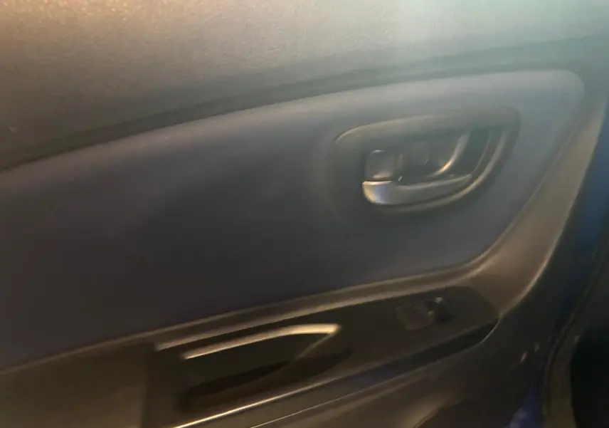Gros plan sur la poignée intérieure et la commande de fenêtre de la porte côté gauche d’une Toyota Yaris bleu 2020.