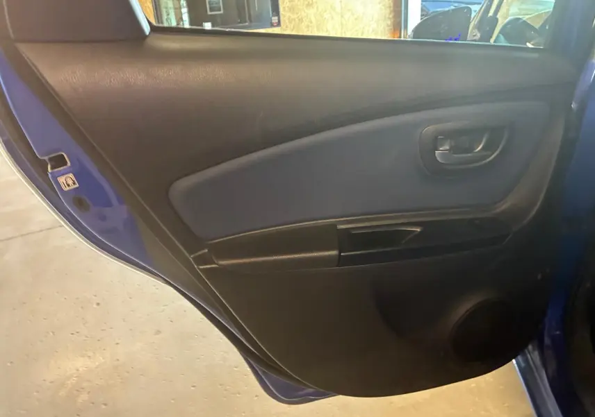 Vue intérieure sur la porte arrière gauche bleu de la Toyota Yaris 2020, avec panneau noir et poignée intégrée.