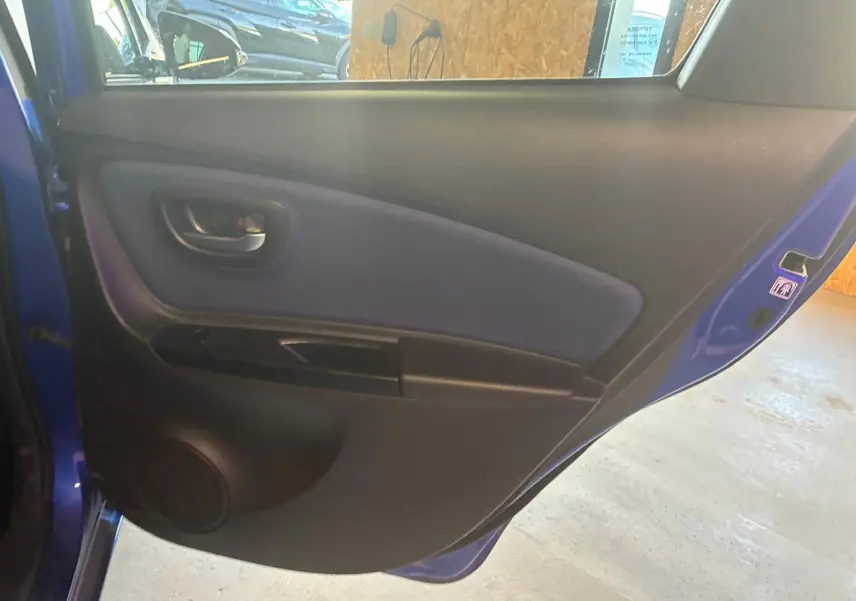 Vue intérieure de la porte arrière gauche bleu foncé d'une Toyota Yaris hybride 2020, avec panneau noir et tissu bleu.