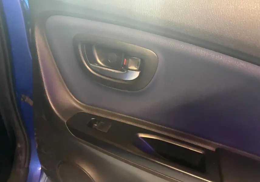 Gros plan sur la poignée intérieure et panneau de porte côté gauche d'une Toyota Yaris bleu 2020, finition hybride.