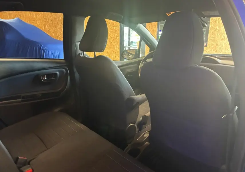 Vue intérieure arrière de la Toyota Yaris hybride 2020, sièges en tissu noir et tableau de bord partiellement visible.