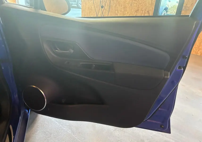 Vue intérieure de la porte avant gauche bleue d'une Toyota Yaris 2020, avec haut-parleur rond et poignée noire.